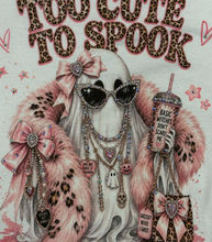 Load image into Gallery viewer, A graphic print on a white fabric featuring a stylized white cat wearing sunglasses, layered necklaces, a pink leopard-print faux fur coat, and holding a drink, with the text 'YOU CUTE TO SPOOK' in leopard-print letters above.